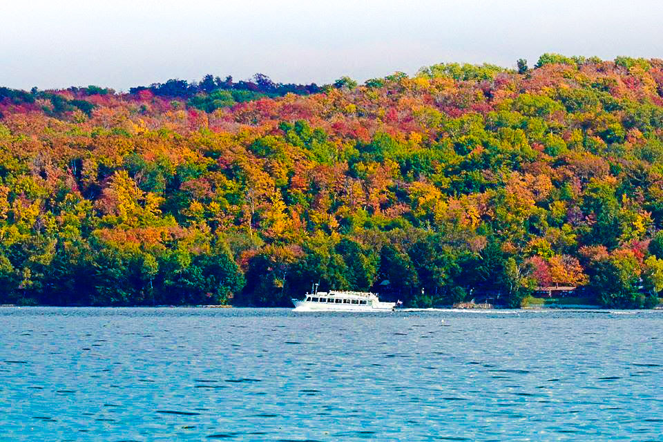 A Pictured Rocks Cruises’ boat glides along Lake Superior shoreline with fall foliage in the background. PC: Pictured Rocks Cruises