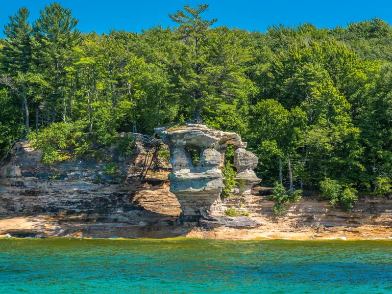 Chapel Rock: Free-standing sandstone formation with a natural arch and lone tree, seen on tours.