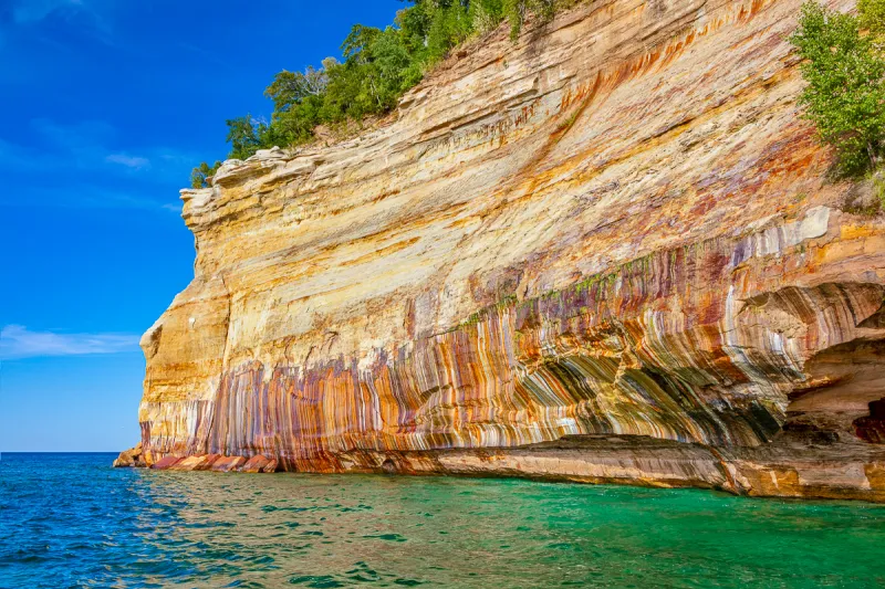 Painted Coves: Multicolored sandstone cliffs, a vibrant highlight of Pictured Rocks cruise tours.